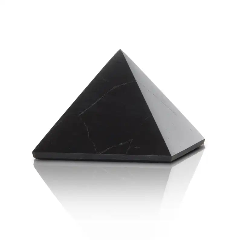 A polished black Shungite stone emf defender placed on a black base.