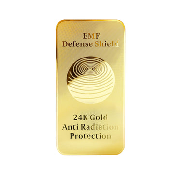 A gold-colored rectangular EMF protection device with the text 'EMF Defense Shield 24K Gold Anti Radiation Protection' on it.