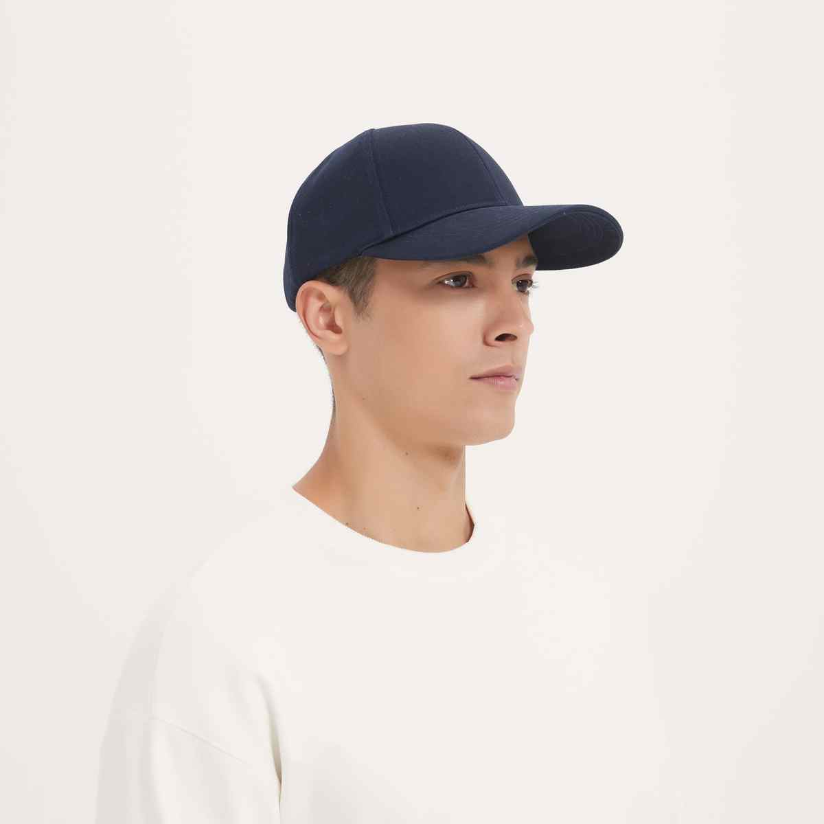 A person wearing a navy blue cap with a brim and a front pouch.