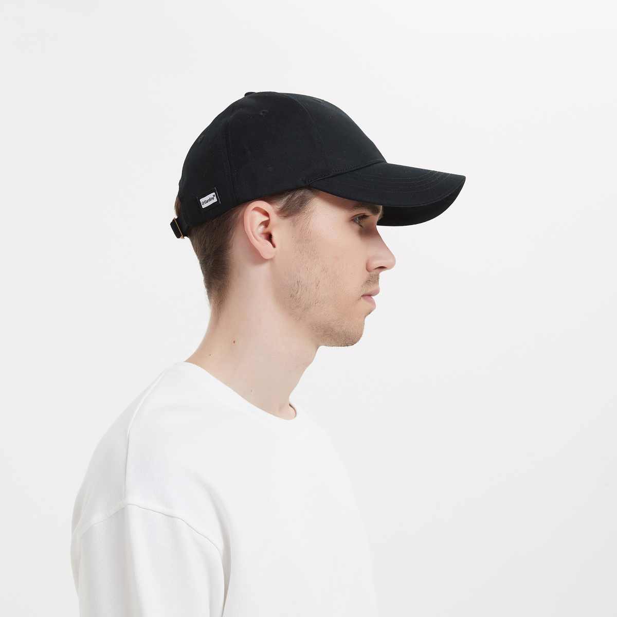 A person wearing a black baseball cap with a logo on the front.